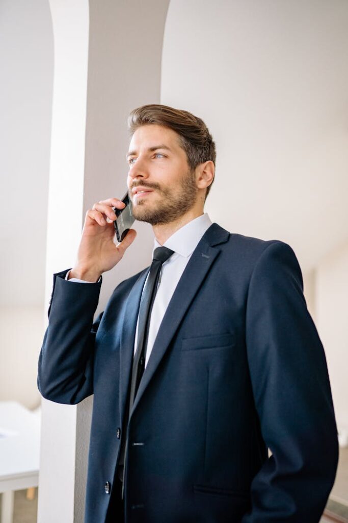 pexels-photo-7693185 Confident businessman in a suit having a phone conversation indoors.